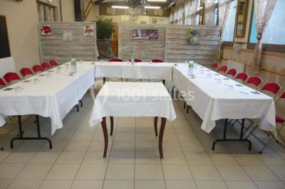 Espace couvert avec canapé, tables et chaises en bois, entouré de verdure visible à travers les ouvertures.