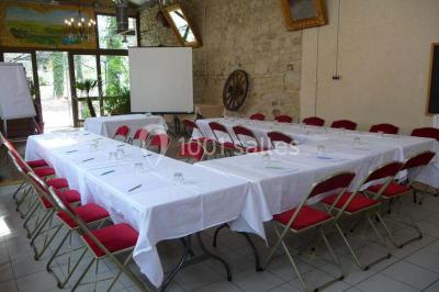Espace couvert avec canapé, tables et chaises en bois, entouré de verdure visible à travers les ouvertures.