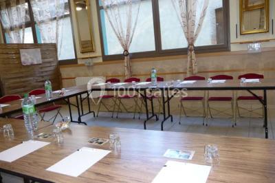 Espace couvert avec canapé, tables et chaises en bois, entouré de verdure visible à travers les ouvertures.