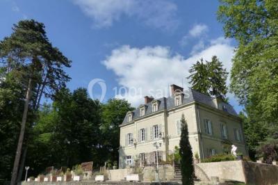 Espace couvert avec canapé, tables et chaises en bois, entouré de verdure visible à travers les ouvertures.