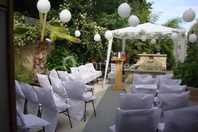 Château gonflable blanc installé sur une surface gravillonnée, entouré de végétation et de mobilier de jardin.