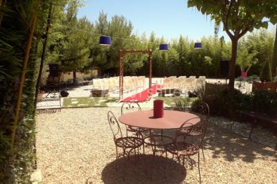 Château gonflable blanc installé sur une surface gravillonnée, entouré de végétation et de mobilier de jardin.