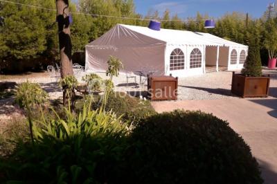 Château gonflable blanc installé sur une surface gravillonnée, entouré de végétation et de mobilier de jardin.