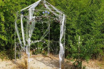 Château gonflable blanc installé sur une surface gravillonnée, entouré de végétation et de mobilier de jardin.