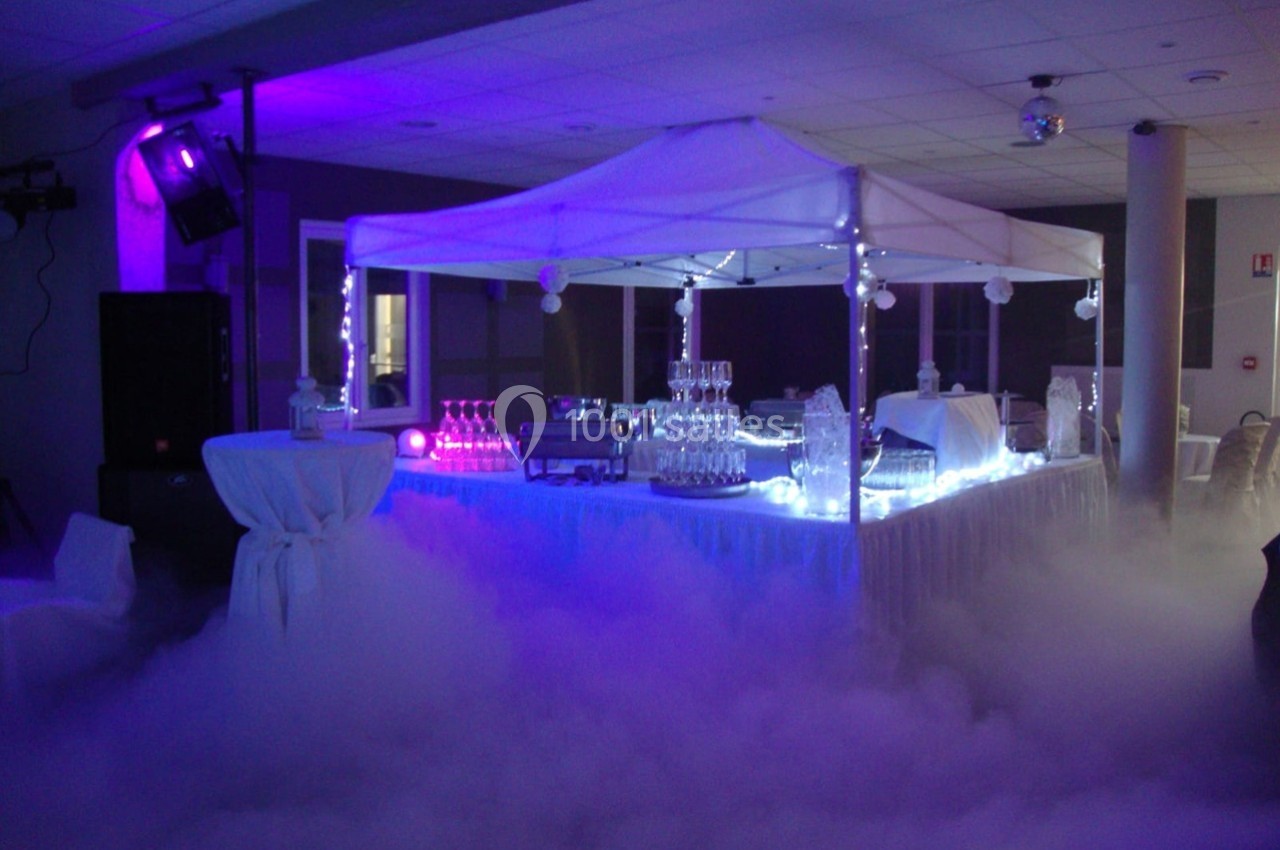 Table de buffet éclairée par des lumières violettes et entourée de fumée dans une salle de réception.