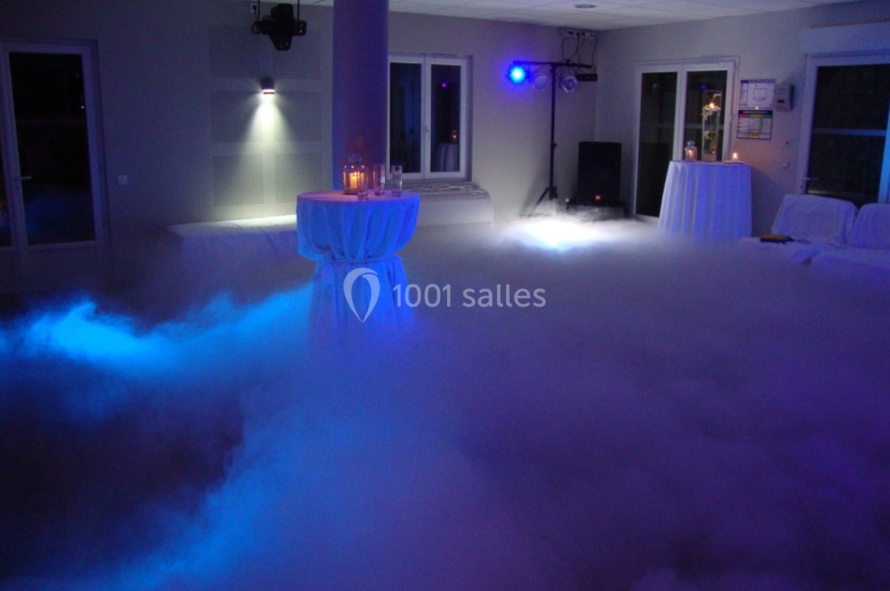 Salle de réception avec éclairage tamisé et sol recouvert d'un épais brouillard artificiel.