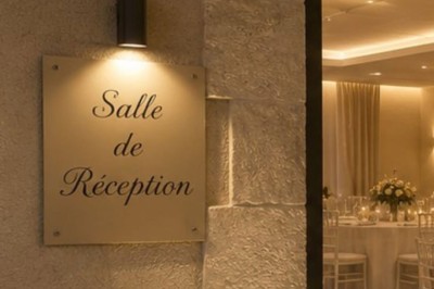 Salle avec parquet, tables basses, fauteuils en cuir sombre, comptoir rouge au fond et ambiance tamisée.
