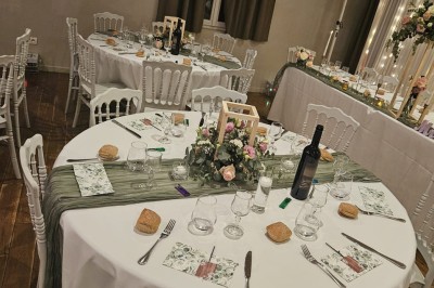 Salle avec parquet, tables basses, fauteuils en cuir sombre, comptoir rouge au fond et ambiance tamisée.