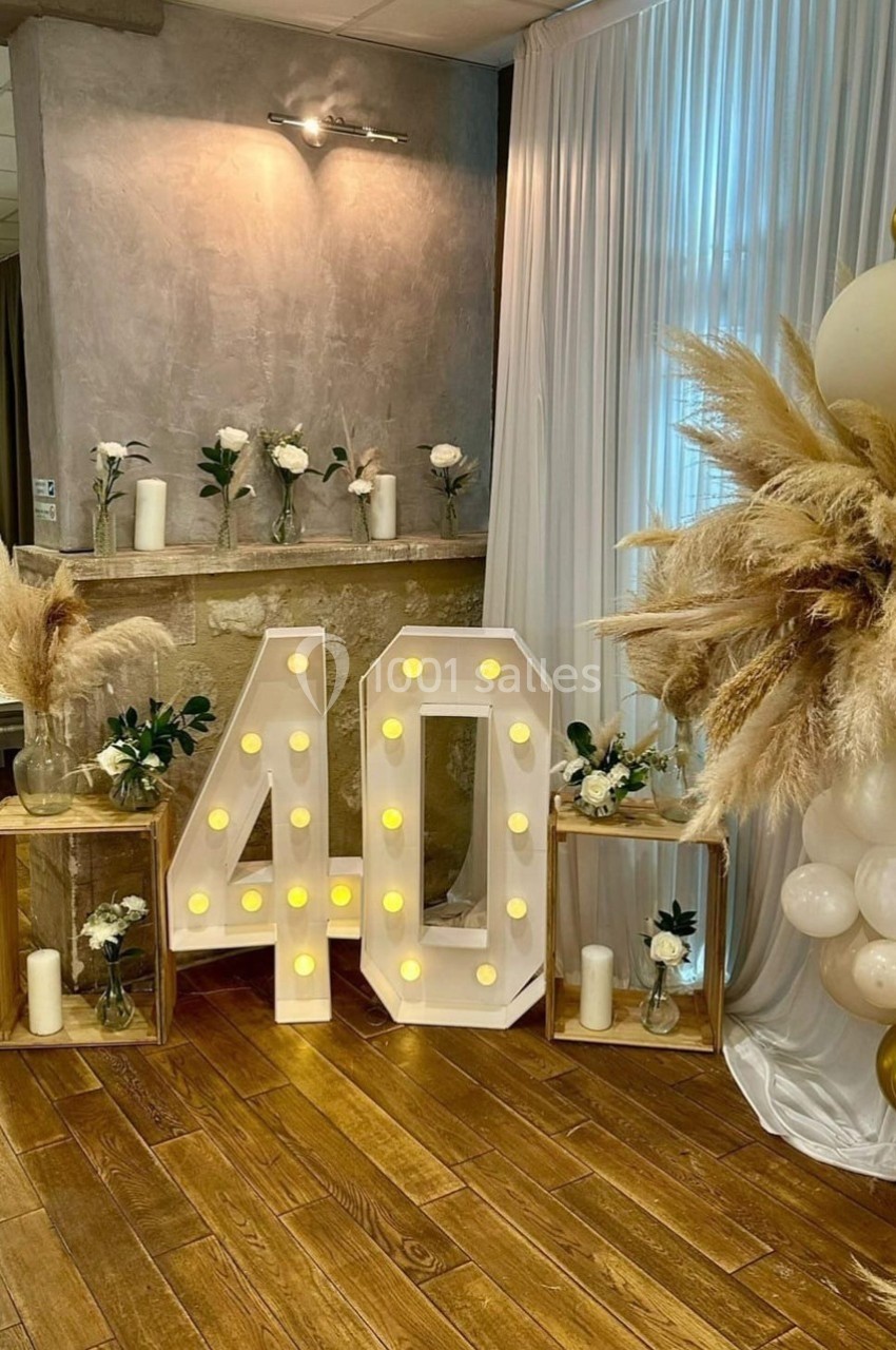Décoration d'anniversaire avec le chiffre 40 lumineux, fleurs blanches, pampas et ballons dans une salle élégante.