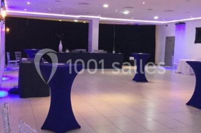 Centre de table décoratif avec bougie, fleurs blanches et roses, entouré de cadeaux sur une table de réception élégante.