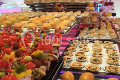 Centre de table décoratif avec bougie, fleurs blanches et roses, entouré de cadeaux sur une table de réception élégante.