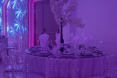 Centre de table décoratif avec bougie, fleurs blanches et roses, entouré de cadeaux sur une table de réception élégante.