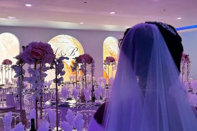 Centre de table décoratif avec bougie, fleurs blanches et roses, entouré de cadeaux sur une table de réception élégante.