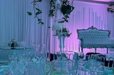 Centre de table décoratif avec bougie, fleurs blanches et roses, entouré de cadeaux sur une table de réception élégante.