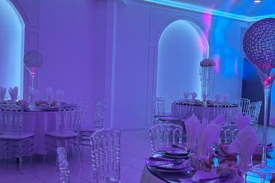 Centre de table décoratif avec bougie, fleurs blanches et roses, entouré de cadeaux sur une table de réception élégante.