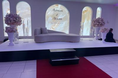 Centre de table décoratif avec bougie, fleurs blanches et roses, entouré de cadeaux sur une table de réception élégante.