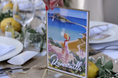 Carte illustrée de Ramatuelle placée sur une table décorée avec des citrons, des verres et une nappe en toile de jute.
