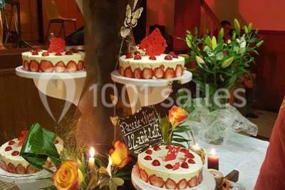 Deux balais déguisés en mariés avec robe et costume, posés devant une tente blanche et un cadre décoratif.