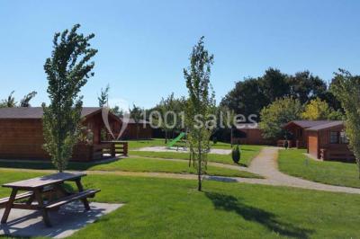 Deux balais déguisés en mariés avec robe et costume, posés devant une tente blanche et un cadre décoratif.