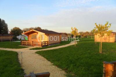 Deux balais déguisés en mariés avec robe et costume, posés devant une tente blanche et un cadre décoratif.