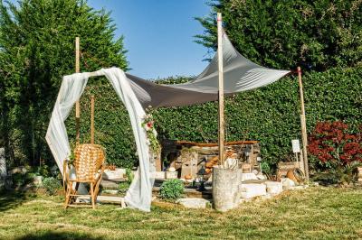 Deux balais déguisés en mariés avec robe et costume, posés devant une tente blanche et un cadre décoratif.