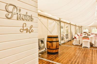 Deux balais déguisés en mariés avec robe et costume, posés devant une tente blanche et un cadre décoratif.