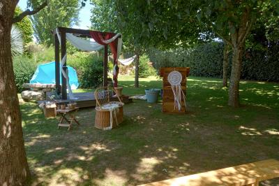 Deux balais déguisés en mariés avec robe et costume, posés devant une tente blanche et un cadre décoratif.