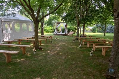 Deux balais déguisés en mariés avec robe et costume, posés devant une tente blanche et un cadre décoratif.