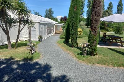 Deux balais déguisés en mariés avec robe et costume, posés devant une tente blanche et un cadre décoratif.