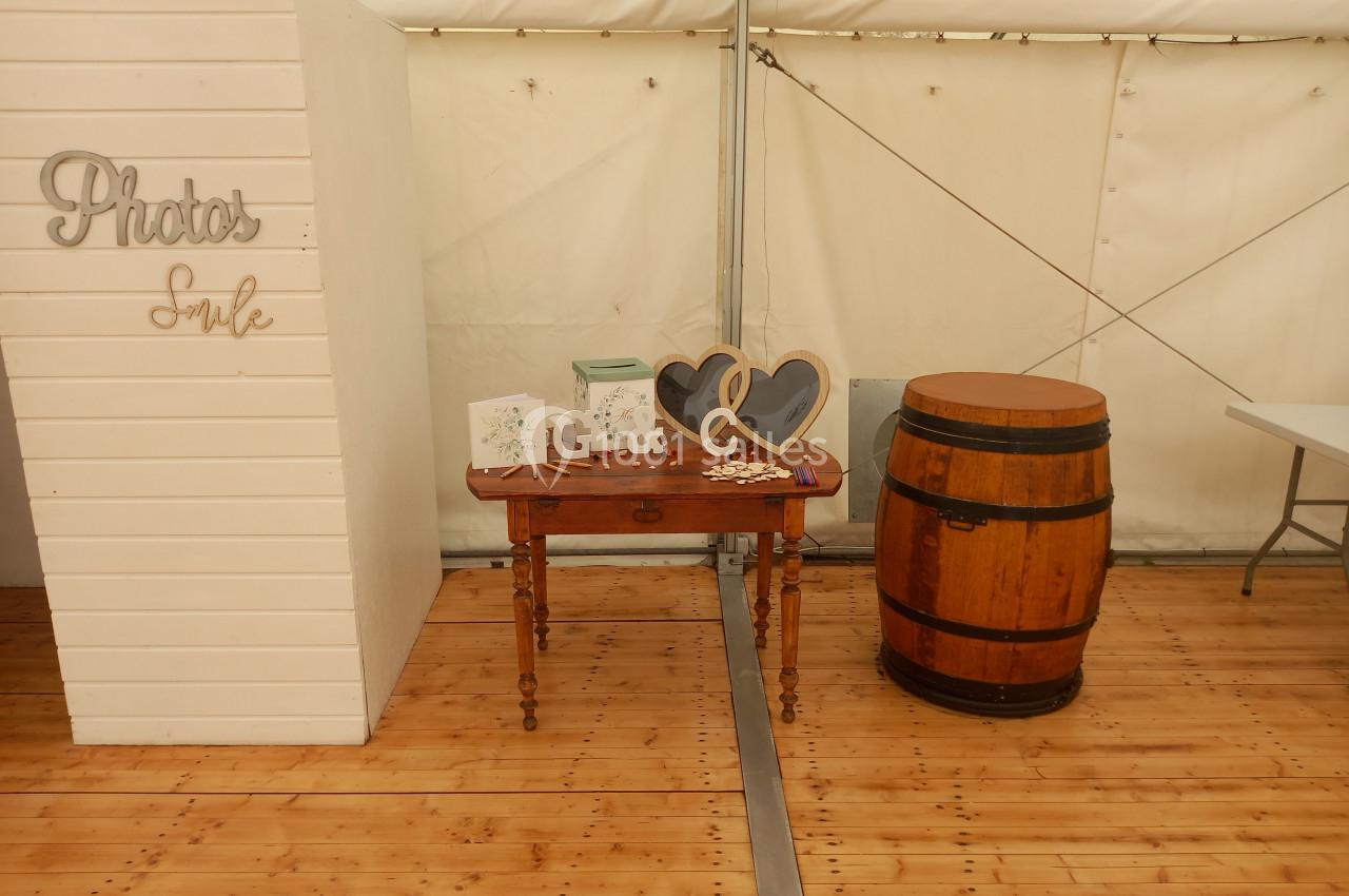 Table en bois avec décorations, deux cadres en forme de cœur, une carte et un tonneau dans une tente sur plancher en bois.