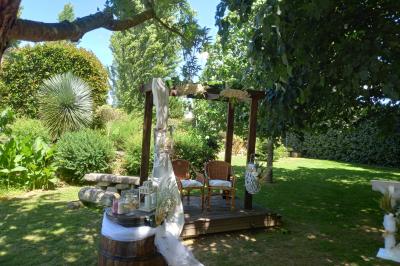 Deux balais déguisés en mariés avec robe et costume, posés devant une tente blanche et un cadre décoratif.