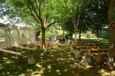 Deux balais déguisés en mariés avec robe et costume, posés devant une tente blanche et un cadre décoratif.