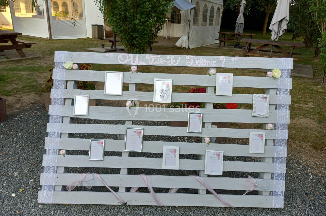 Palette en bois peinte en blanc, décorée de fleurs et rubans, affichant des cartes avec des noms ou messages.