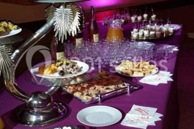 Intérieur d'une tente de réception décorée avec des tables rondes dressées, des chaises blanches et des fleurs.