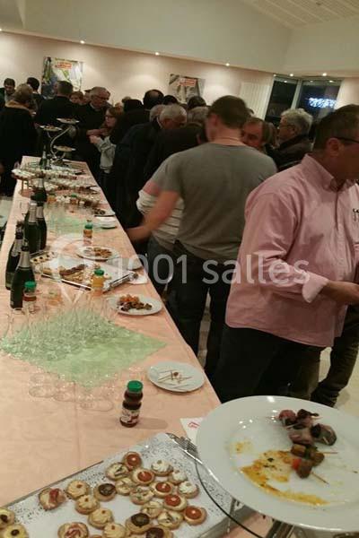 Groupe de personnes rassemblées autour d'une table garnie de plats et boissons lors d'un buffet en intérieur.