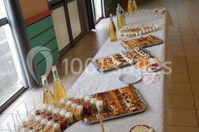 Intérieur d'une tente de réception décorée avec des tables rondes dressées, des chaises blanches et des fleurs.