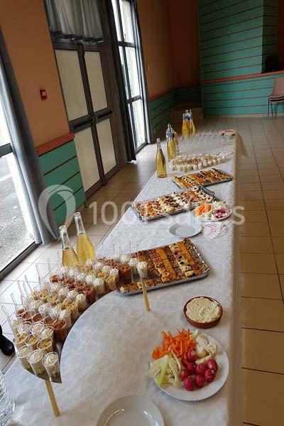 Buffet avec verrines, brochettes apéritives, légumes croquants et boissons disposés sur une longue table blanche.