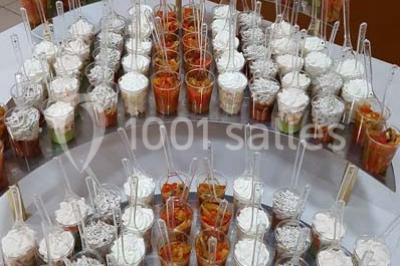 Intérieur d'une tente de réception décorée avec des tables rondes dressées, des chaises blanches et des fleurs.