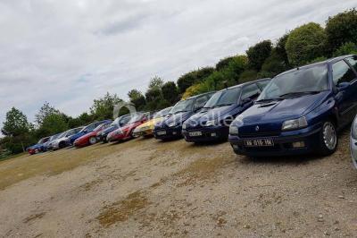 Intérieur d'une tente de réception décorée avec des tables rondes dressées, des chaises blanches et des fleurs.