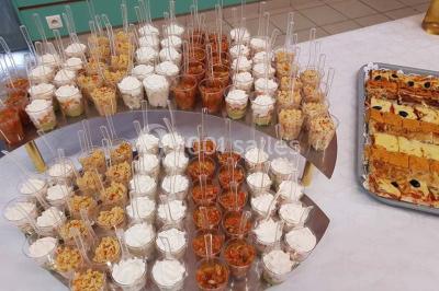 Intérieur d'une tente de réception décorée avec des tables rondes dressées, des chaises blanches et des fleurs.