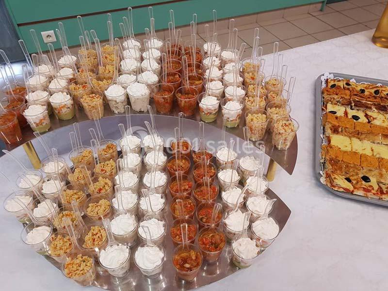 Plateau de verrines variées et parts de quiches disposés sur une table pour un buffet.