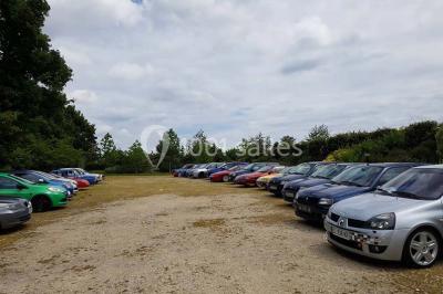 Intérieur d'une tente de réception décorée avec des tables rondes dressées, des chaises blanches et des fleurs.