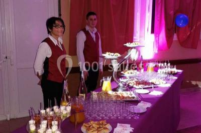 Intérieur d'une tente de réception décorée avec des tables rondes dressées, des chaises blanches et des fleurs.