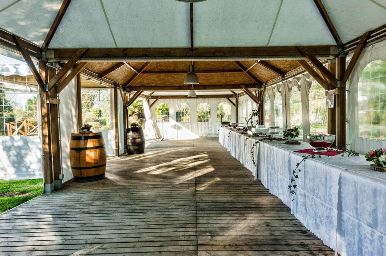 Salle de réception en bois avec tables dressées, tonneaux décoratifs et lumière naturelle entrant par des parois…