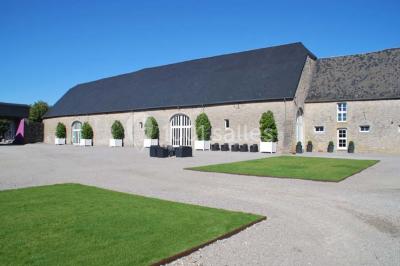 Voûte en briques rouges avec piliers en pierre, sol carrelé gris et mur en pierre apparente.
