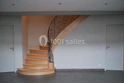 Voûte en briques rouges avec piliers en pierre, sol carrelé gris et mur en pierre apparente.