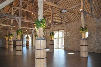Voûte en briques rouges avec piliers en pierre, sol carrelé gris et mur en pierre apparente.