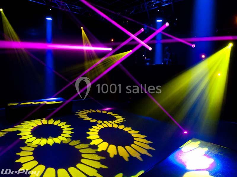 Jeux de lumières colorées projetés dans une salle sombre avec des motifs circulaires au sol.