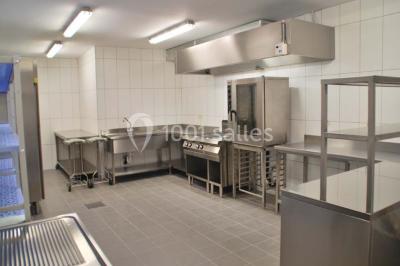 Voûte en briques rouges avec piliers en pierre, sol carrelé gris et mur en pierre apparente.