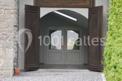 Voûte en briques rouges avec piliers en pierre, sol carrelé gris et mur en pierre apparente.